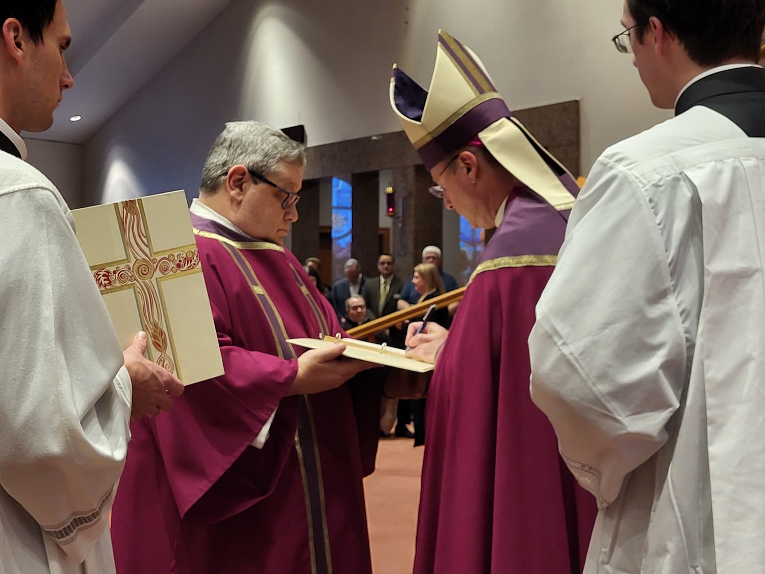 Bishop W. Shawn McKnight signs the Book of the Elect, containing the signatures of people throughout the diocese who are seeking initiation through Baptism and Confirmation at Easter.